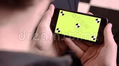 特写男人拿着绿色屏幕的手机。 库存录像。 男人拿着新智能手机，看着绿色屏幕